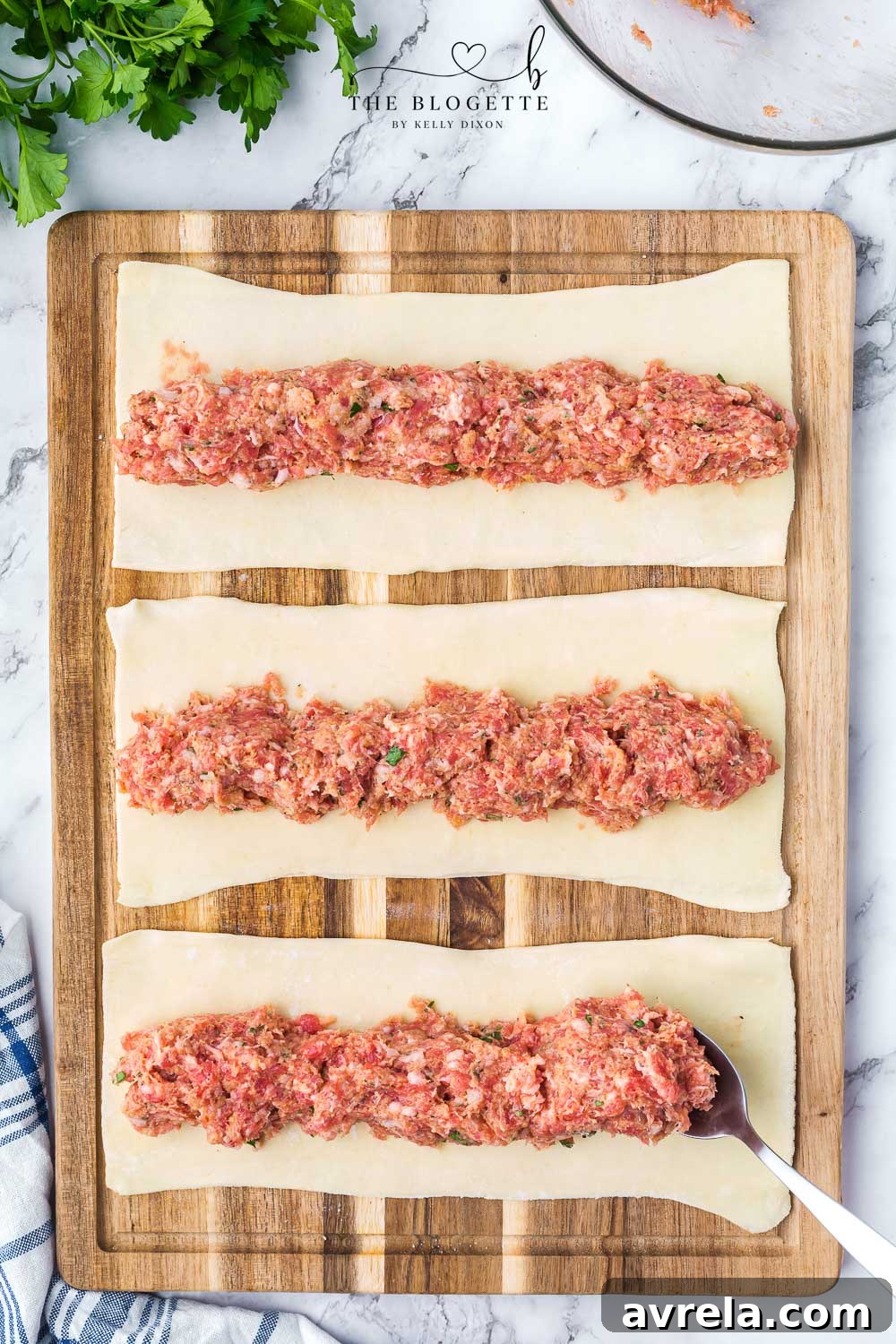 Sausage meat mixture carefully placed onto strips of puff pastry dough, ready for rolling.