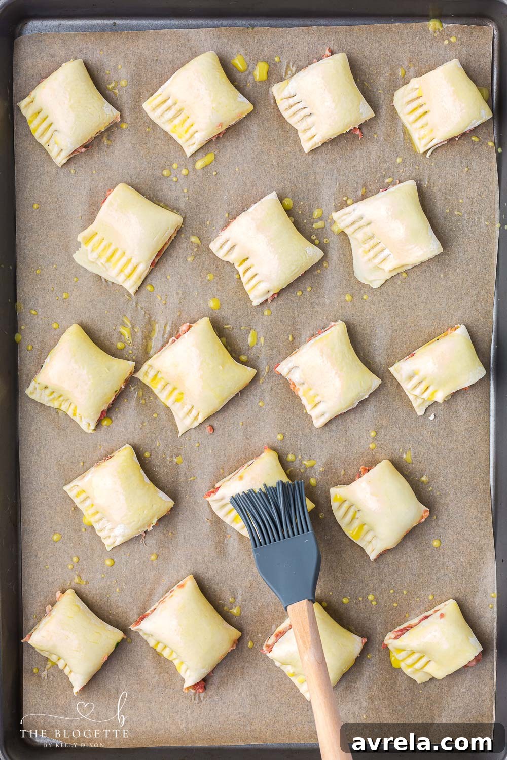 Raw sausage rolls brushed with egg wash, ready for baking in the oven.