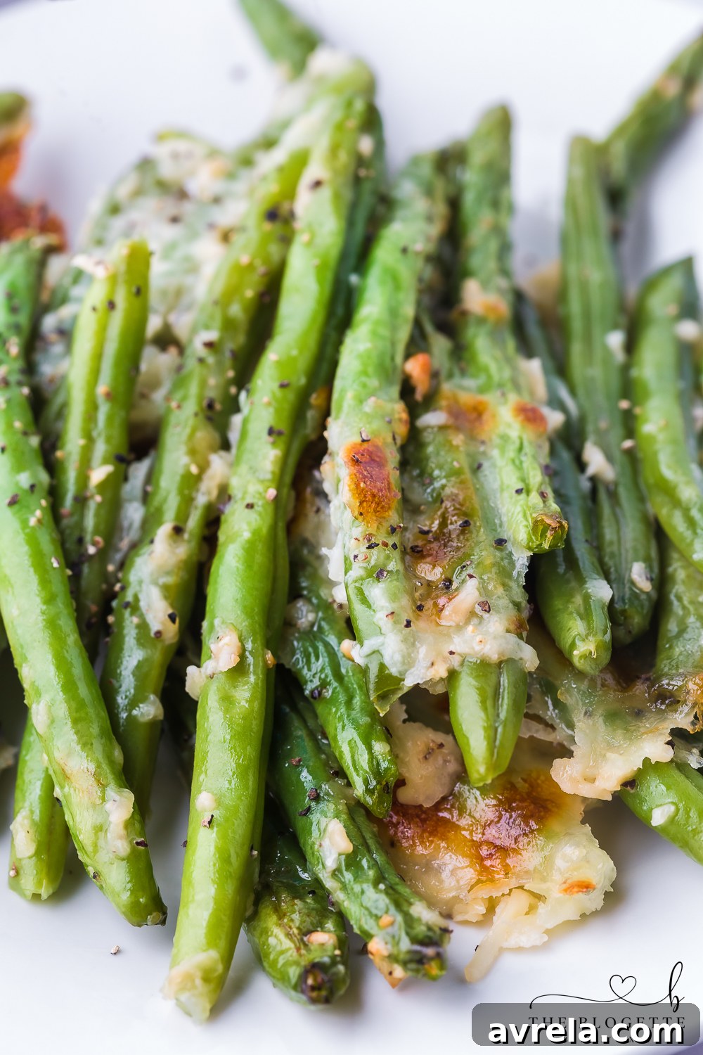 A beautifully presented serving of cheesy garlic baked green beans, garnished with fresh herbs, ready for a holiday meal or family dinner.