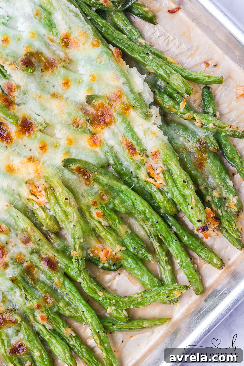 A serving dish filled with piping hot cheesy garlic baked green beans, garnished with fresh parsley, ready to be enjoyed as a vibrant side.