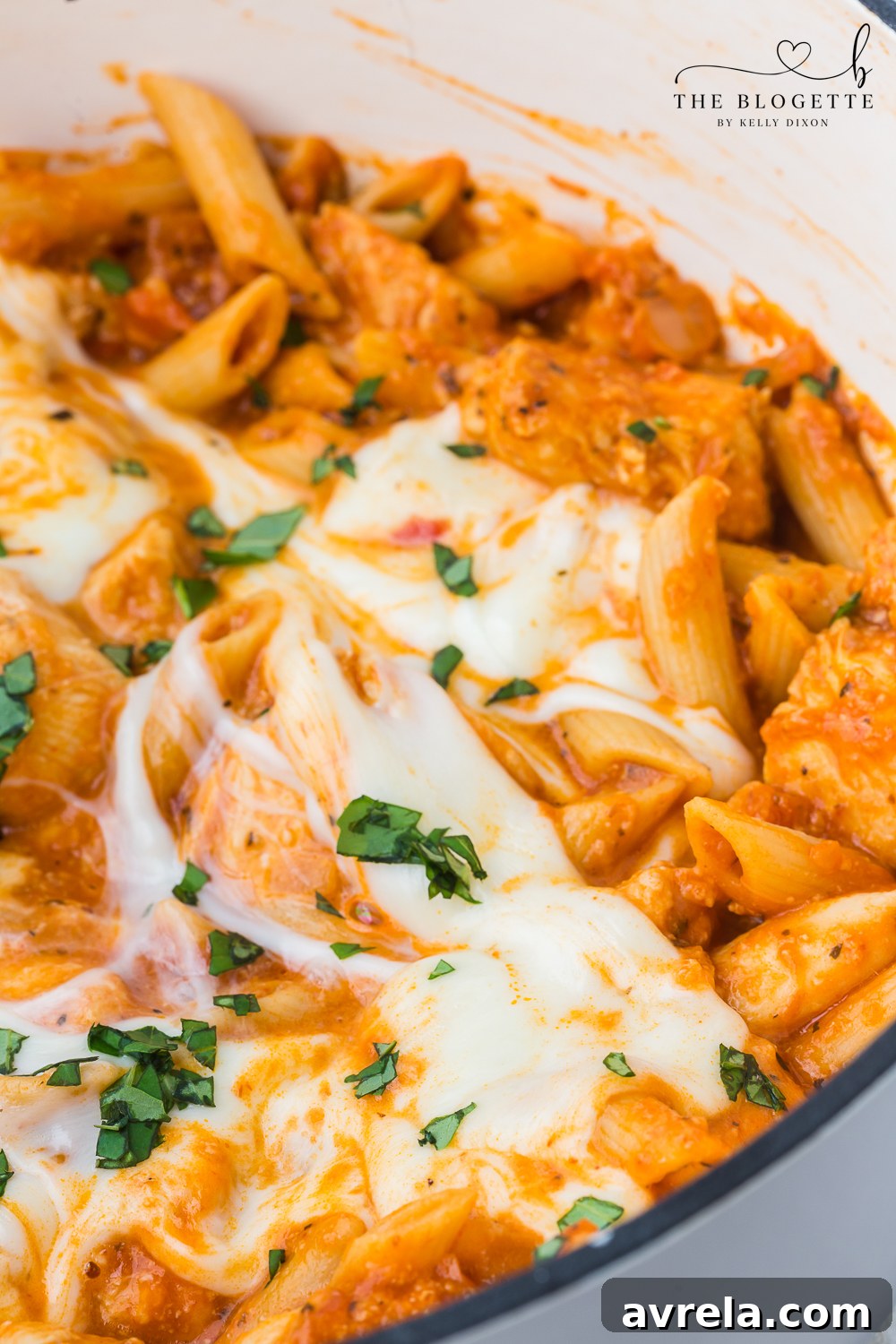 Creamy Chicken Parmesan Pasta 3 Close-up of bubbling Chicken Parmesan Pasta in a large pot with melted cheese and fresh basil garnish.