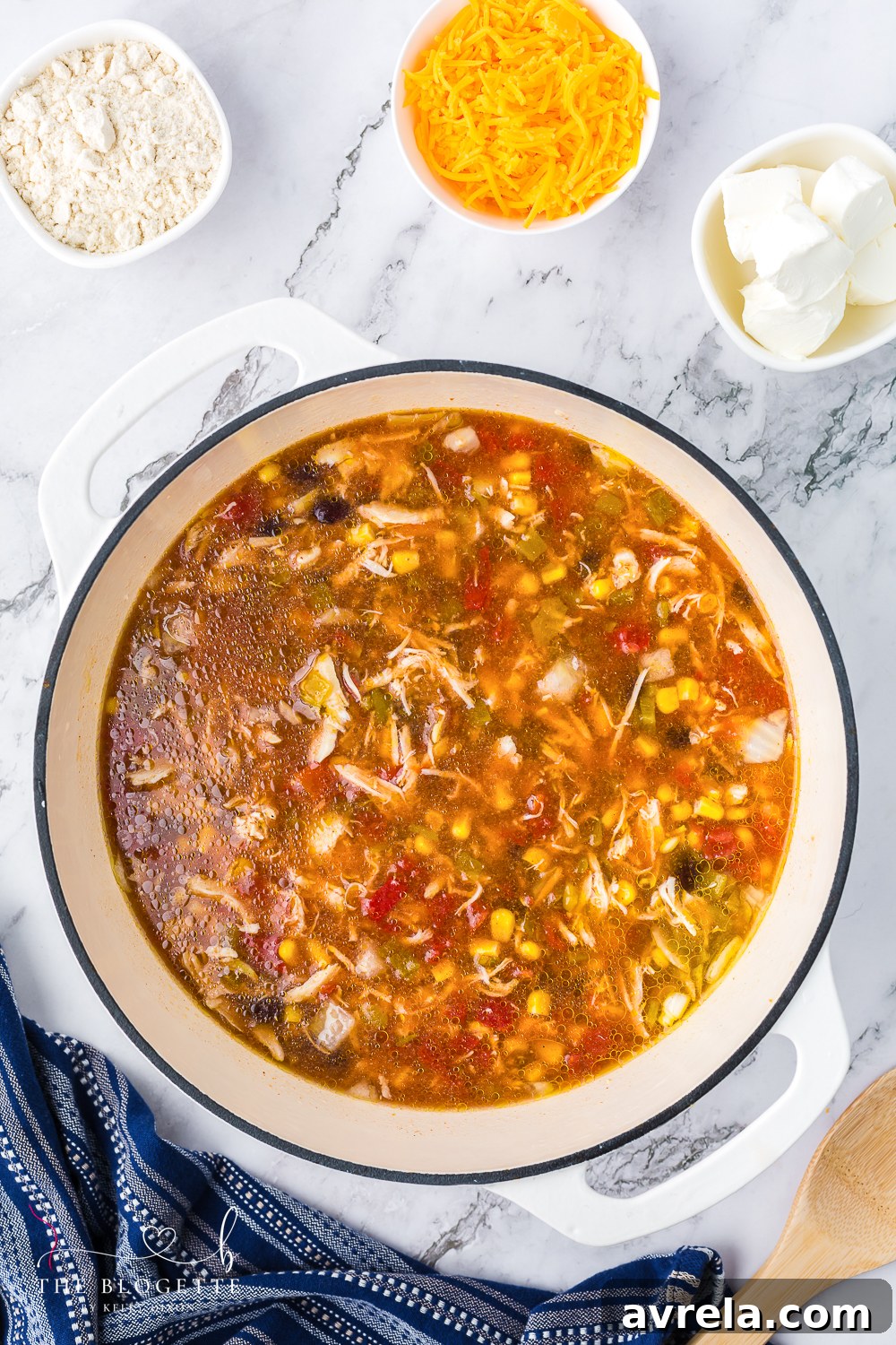 Adding chicken broth and other ingredients to create the rich base of the chicken enchilada soup.