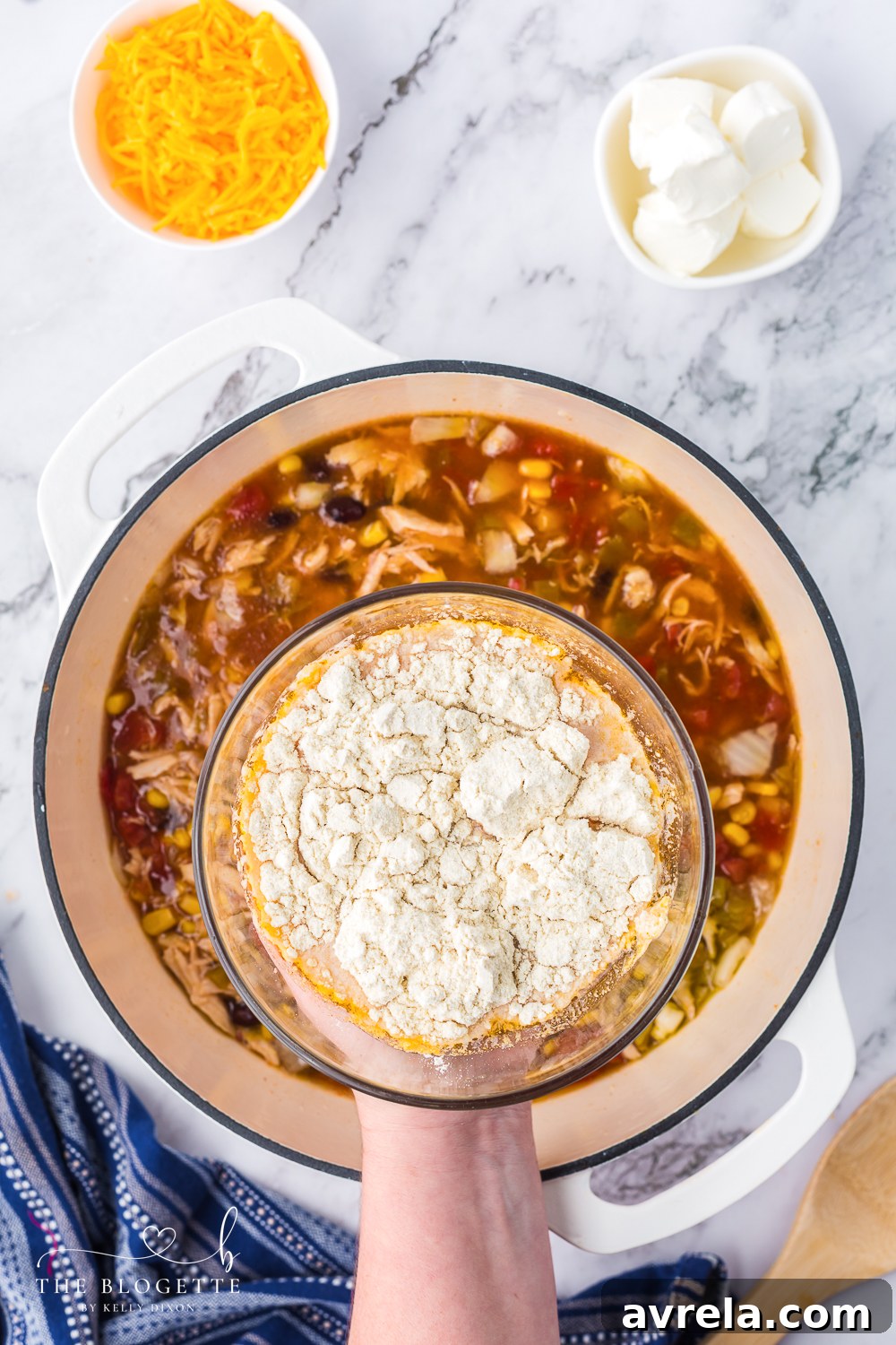 Whisking corn flour into a portion of warm soup to create a smooth, lump-free thickening agent.