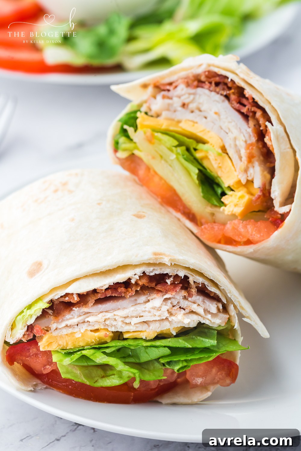 A perfectly rolled Turkey Ranch Club Wrap, showcasing a cross-section of fresh ingredients: turkey, crispy bacon, cheddar cheese, sliced tomato, and crisp romaine lettuce, all drizzled with creamy ranch dressing. This easy and delicious wrap is ideal for a quick lunch or dinner.