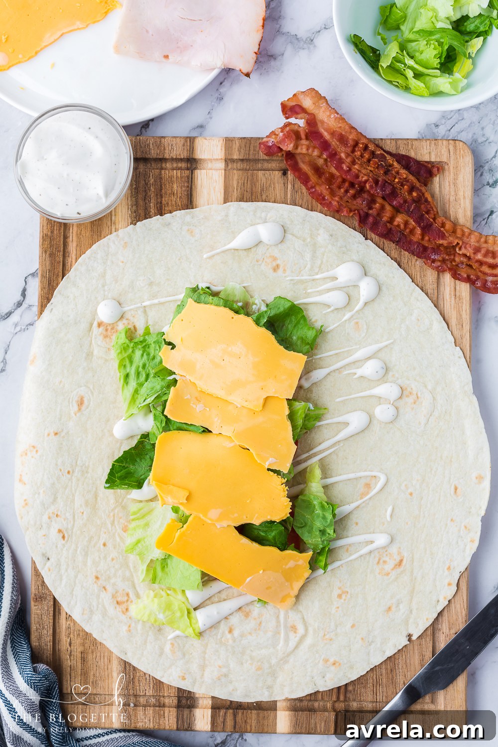 Freshly chopped romaine lettuce and slices of cheddar cheese, prepared for the easy Turkey Ranch Club Wrap recipe.