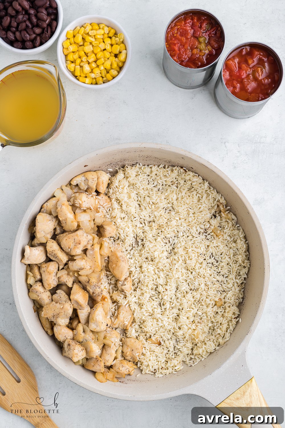 Chicken and rice cooking in a large skillet, midway through preparation.