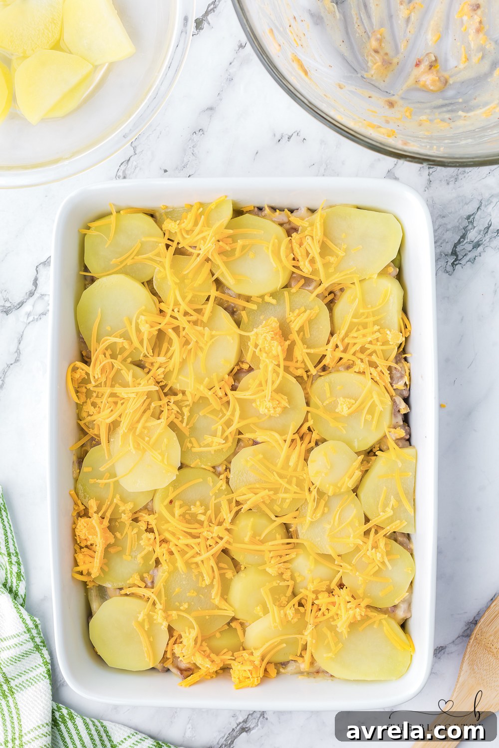 Hearty Beef and Potato Bake 9 Layered casserole with sliced potatoes visible, topped with a generous sprinkle of shredded cheese.