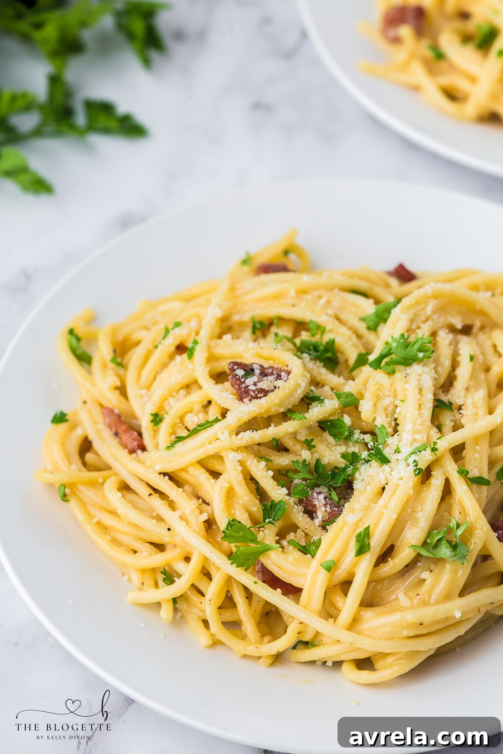 A close-up of a generous serving of Spaghetti Carbonara in a white bowl, garnished with a sprinkle of fresh black pepper and parsley, showcasing its irresistible appeal and creamy texture.