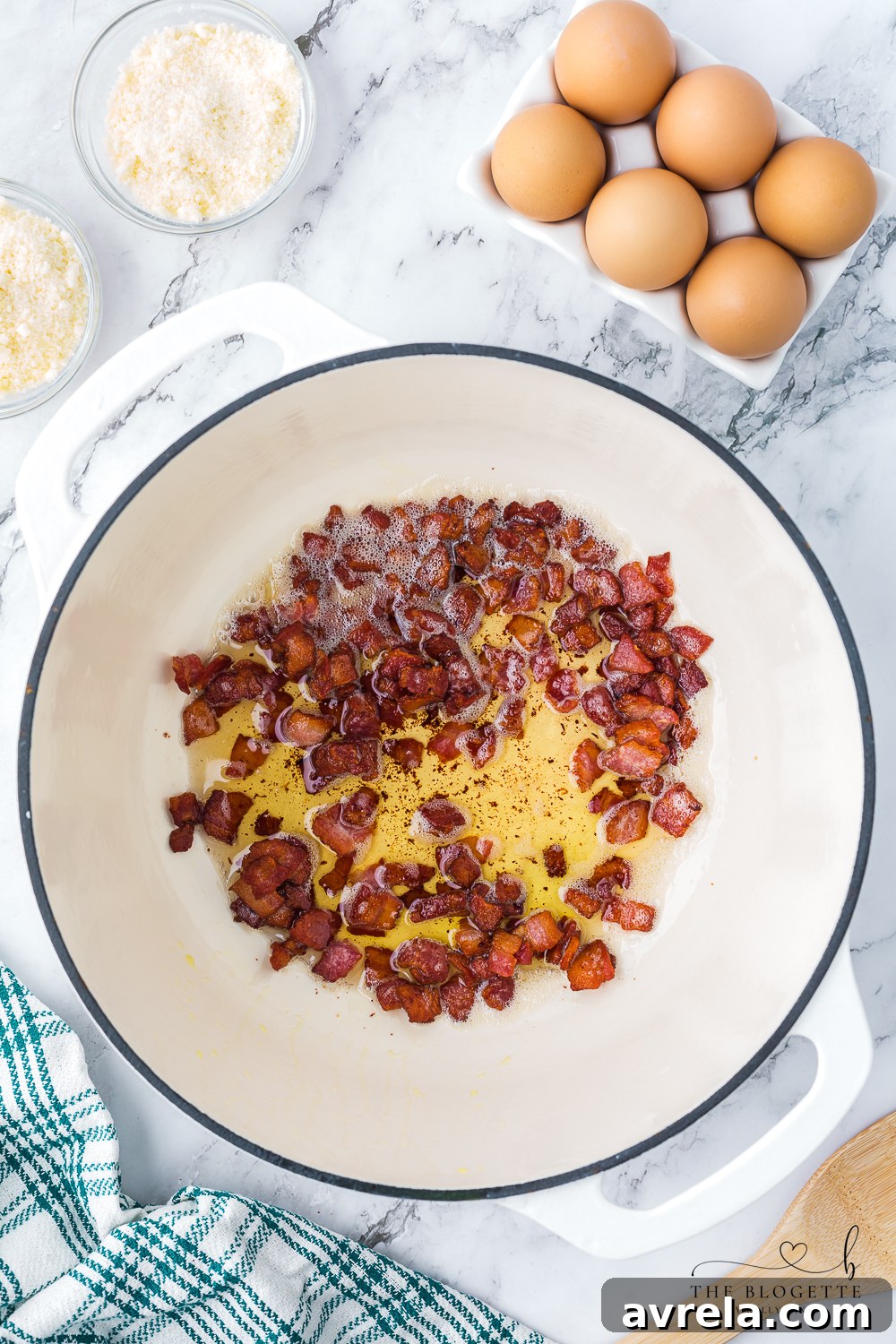 Diced thick-cut bacon sizzling in a large heavy-bottomed skillet, rendering fat and becoming crispy, a crucial first step in making perfect Spaghetti Carbonara.