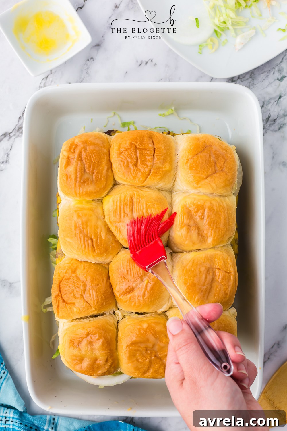 Mini Big Mac Bites 15 A pastry brush applying melted butter to the tops of the slider buns.