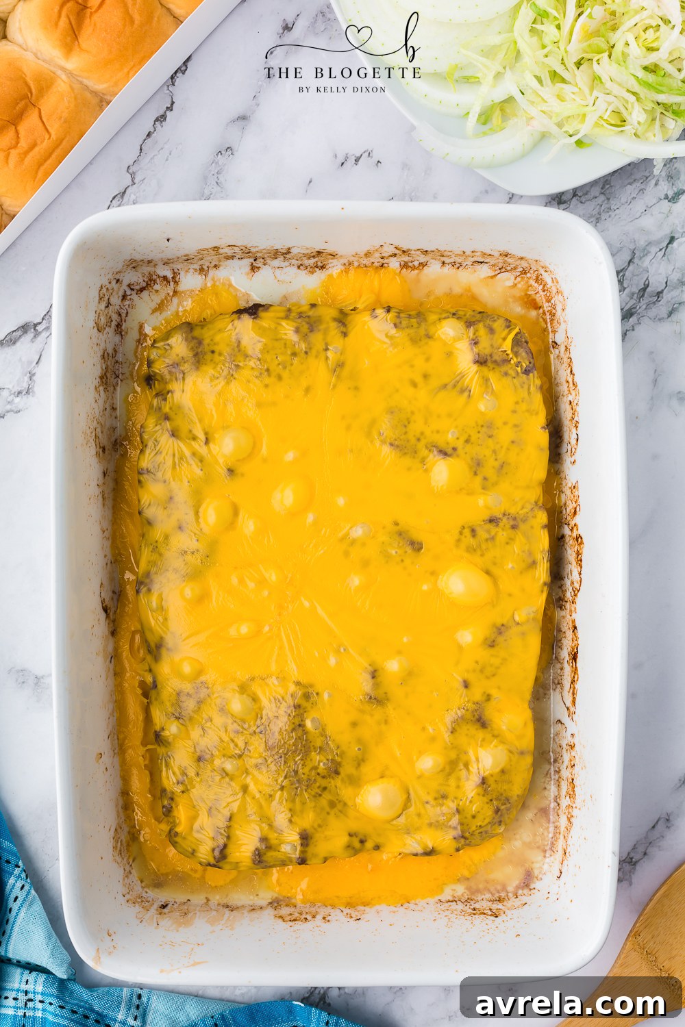 Mini Big Mac Bites 8 Melted American cheese slices covering a baked ground beef patty in a baking dish.