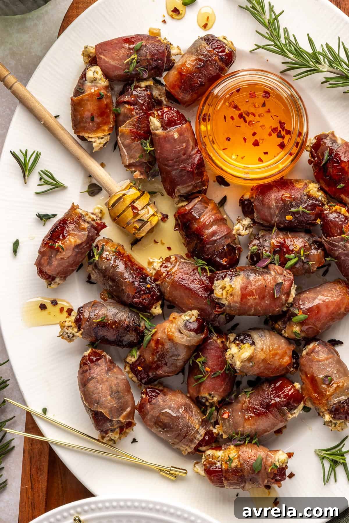 Hot Honey Prosciutto Dates with Creamy Goat Cheese 2 Holiday appetizer: prosciutto wrapped stuffed dates with goat cheese and hot honey on platter with honey dipper