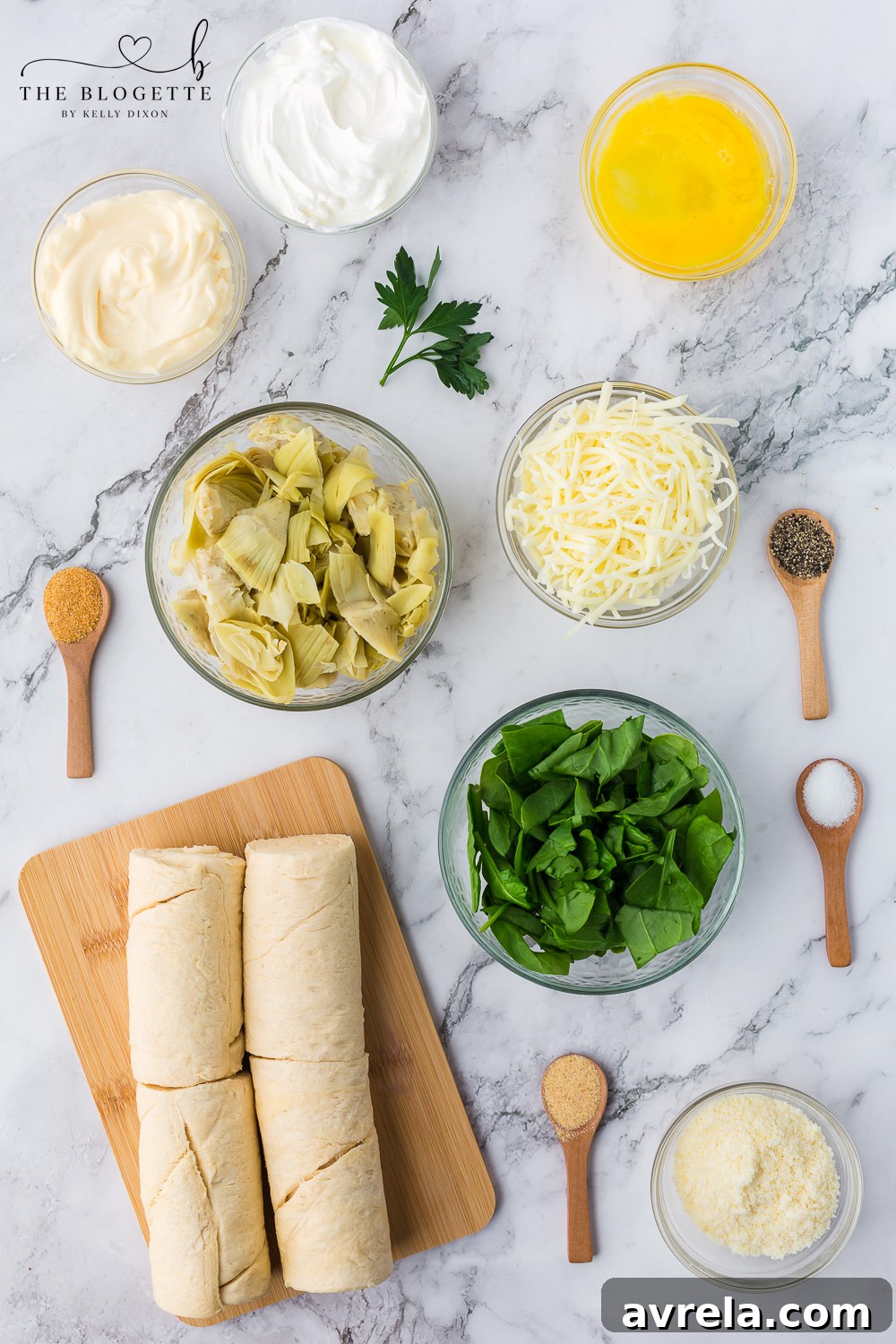 A vibrant display of fresh ingredients, including spinach, artichoke hearts, various cheeses, and seasonings, laid out for the pinwheel recipe.