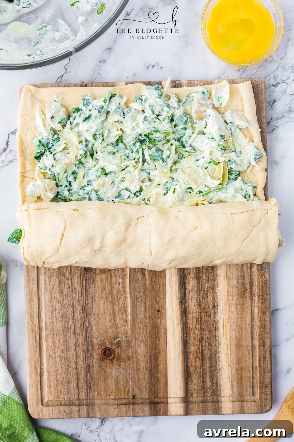 The crescent dough tightly rolled up into a perfect log shape with the spinach artichoke filling securely inside.