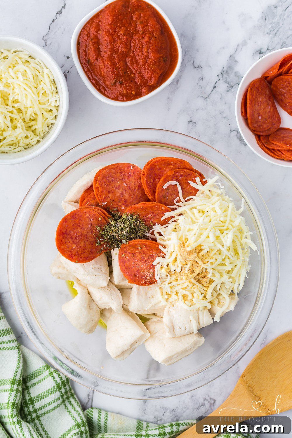 Cheesy Pizza Pull-Apart Bread 5 Mixing biscuit quarters, cheese, and pepperoni in a large bowl.