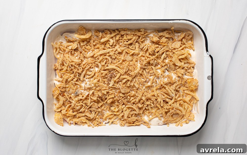 Crispy fried onions sprinkled over the sauced pork chops in a baking dish before baking.