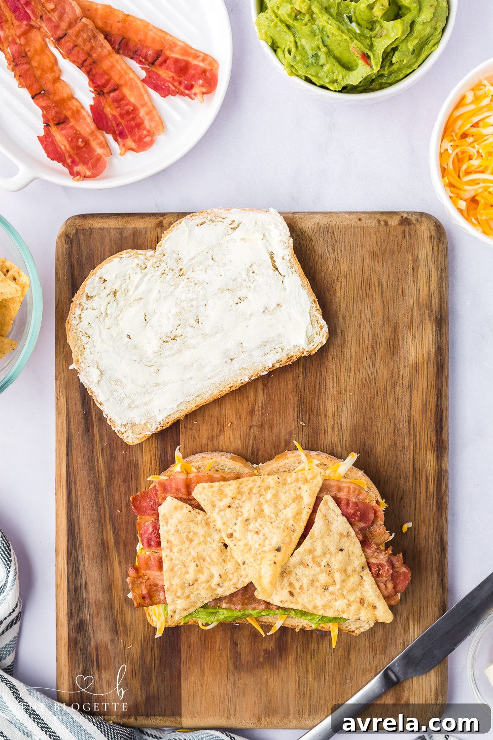 Layering crunchy tortilla chips into a Bacon Guacamole Grilled Cheese Sandwich for added texture.