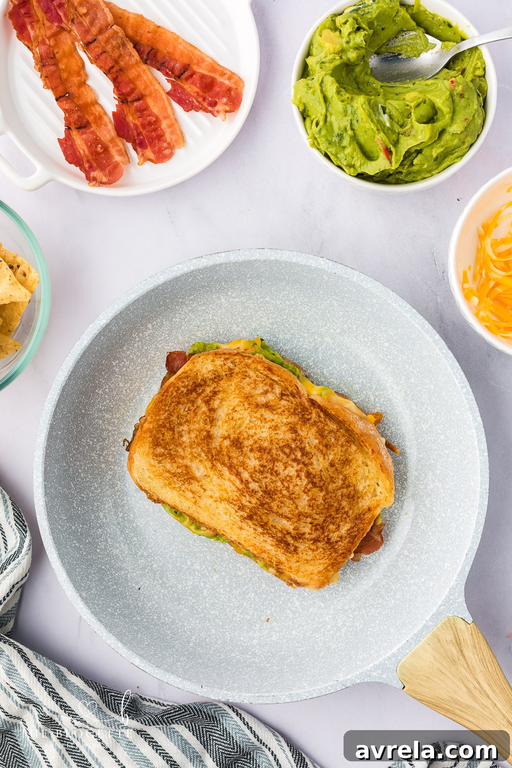 A Bacon Guacamole Grilled Cheese Sandwich grilling to a perfect golden brown in a hot skillet.