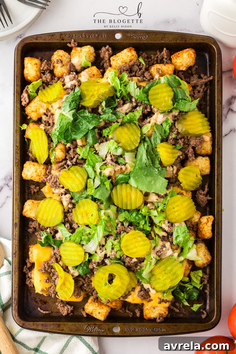 The final delicious plate of Cheeseburger Totchos, piled high with sauce, pickles, and lettuce.