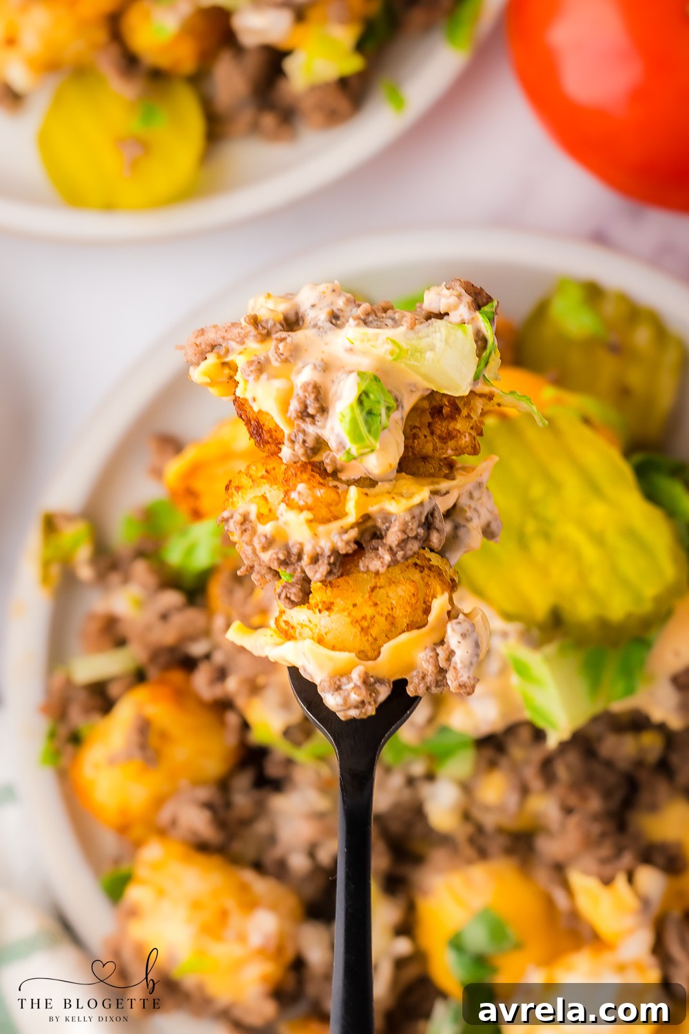 Cheeseburger Totchos on a rustic wooden table, with a vibrant topping of sauce, pickles, and lettuce, emphasizing their delicious appeal.