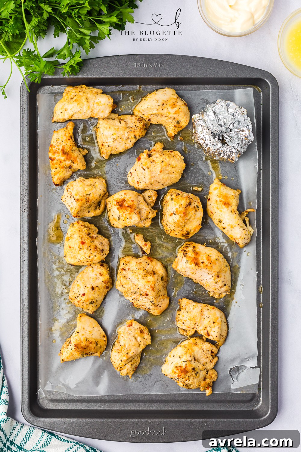 The baking sheet featuring roasted chicken and garlic, cooked to perfection with a golden-brown finish and tender consistency, ready for the next step.