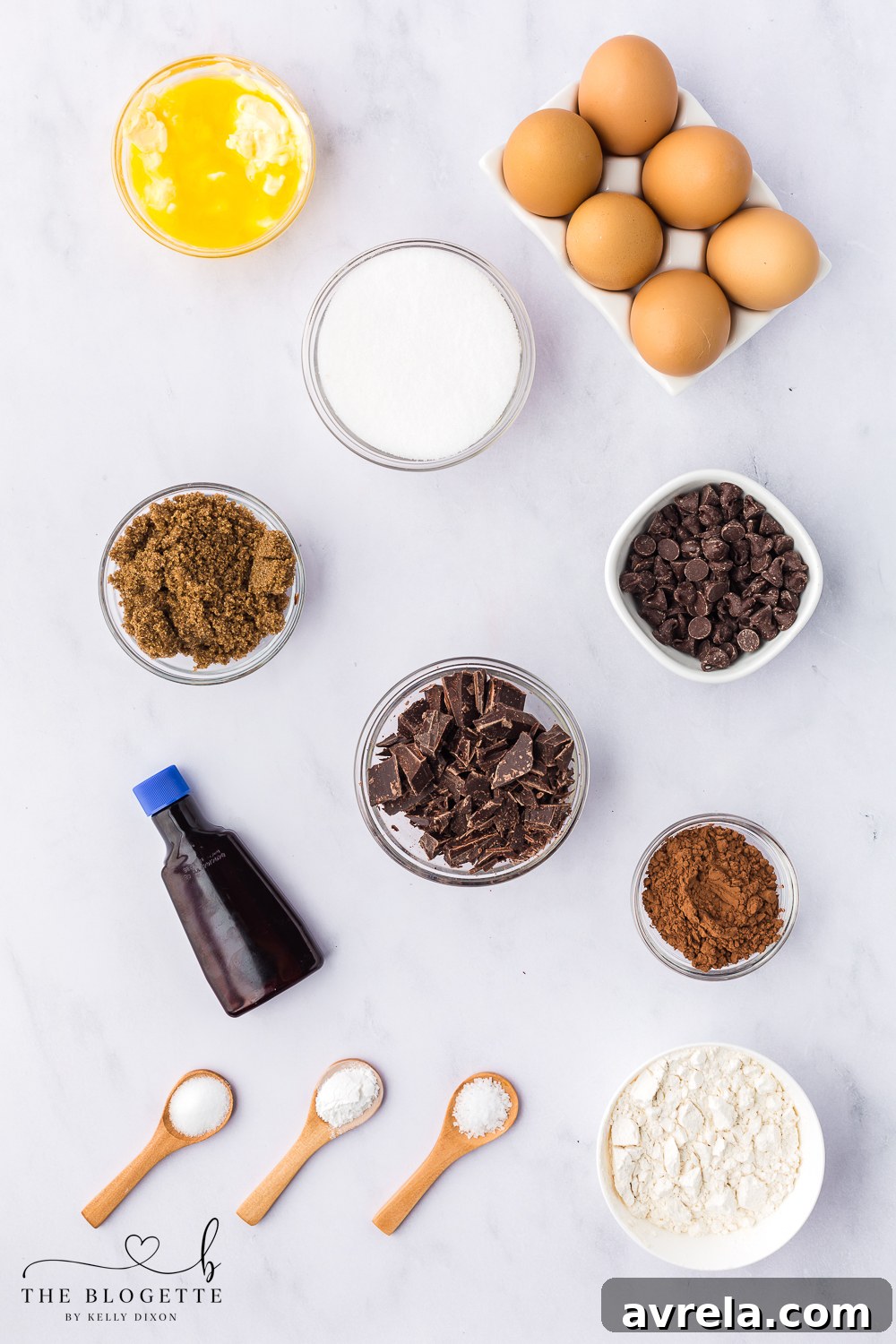 Various ingredients for chocolate brownie cookies neatly arranged on a white background, including chocolate, butter, eggs, and flour.