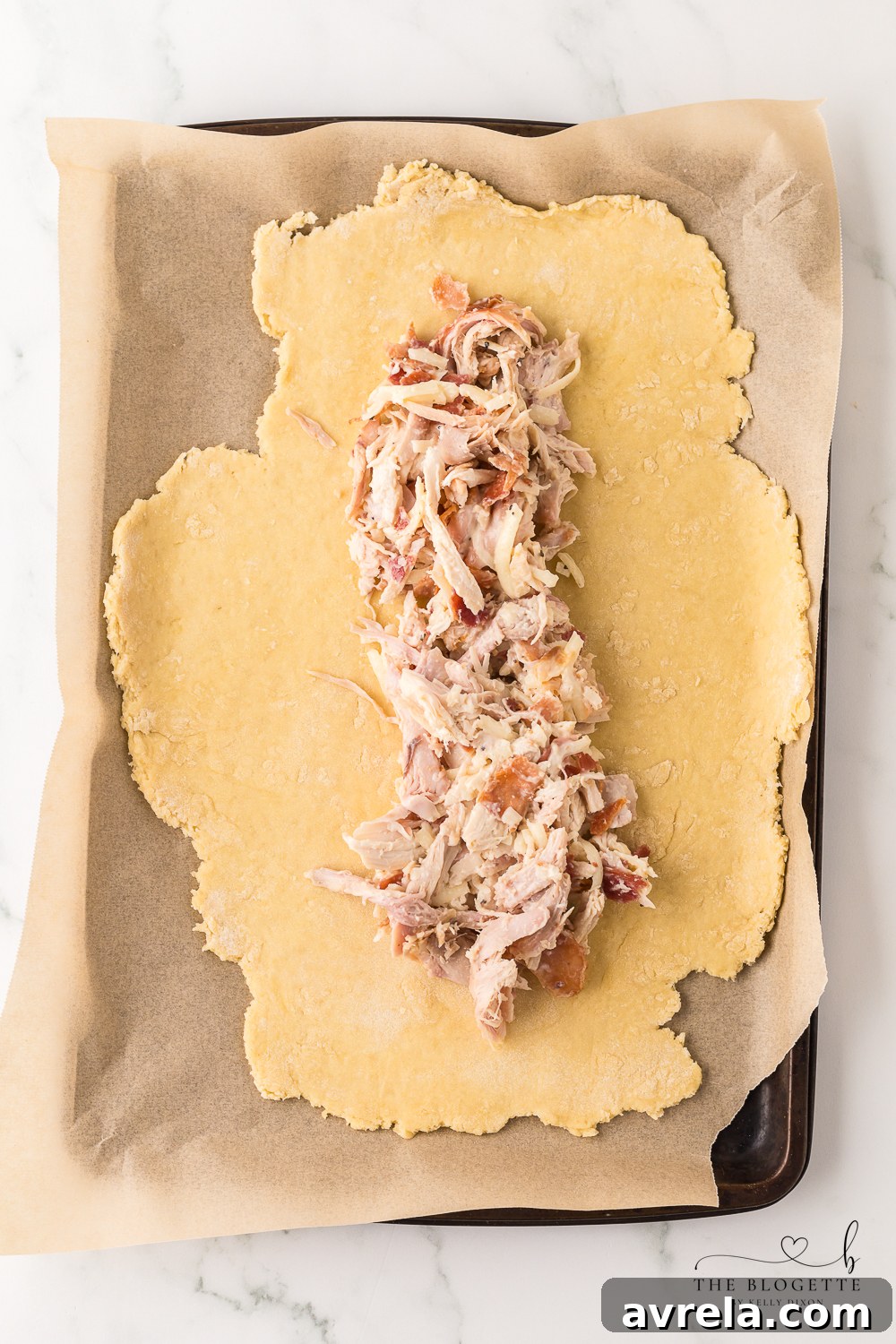 Chicken mixture spread over rolled-out pizza dough, ready to be folded and sealed.