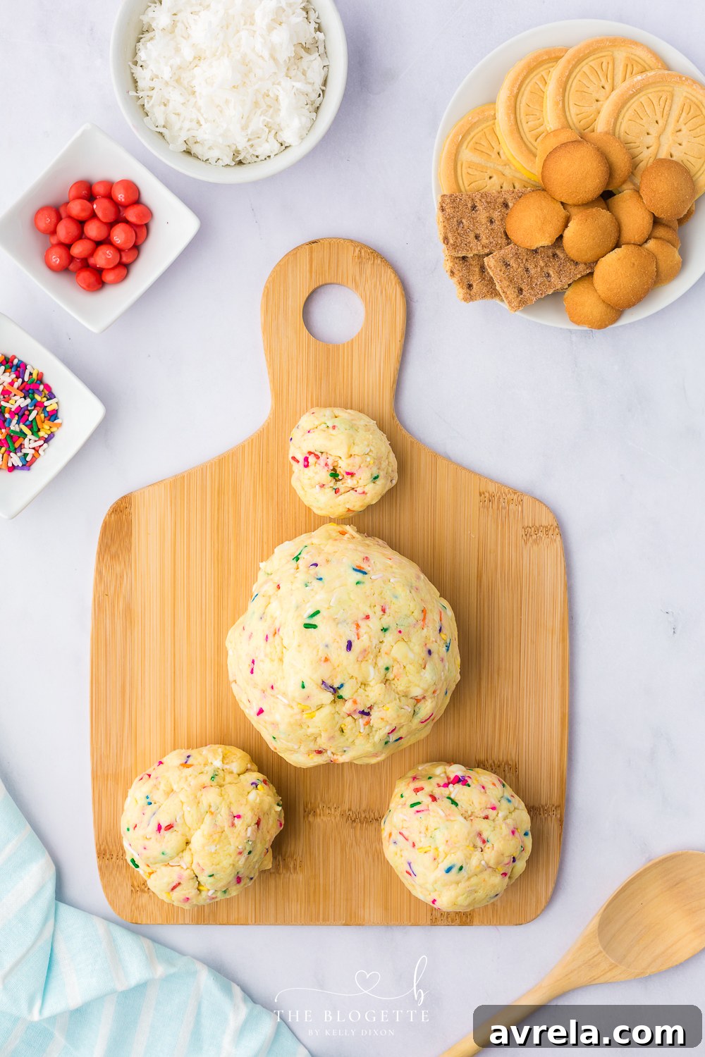 The Bunny Butt Cheeseball mixture divided and rolled into one large ball, two medium balls shaped into teardrops, and one small ball, ready for chilling.