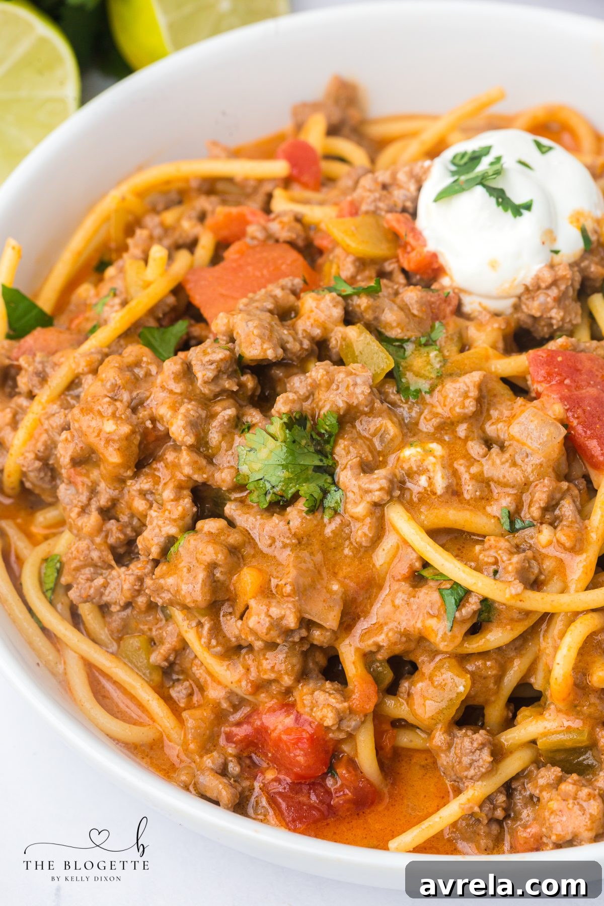 A bowl of delicious Taco Spaghetti garnished with fresh cilantro and a lime wedge.