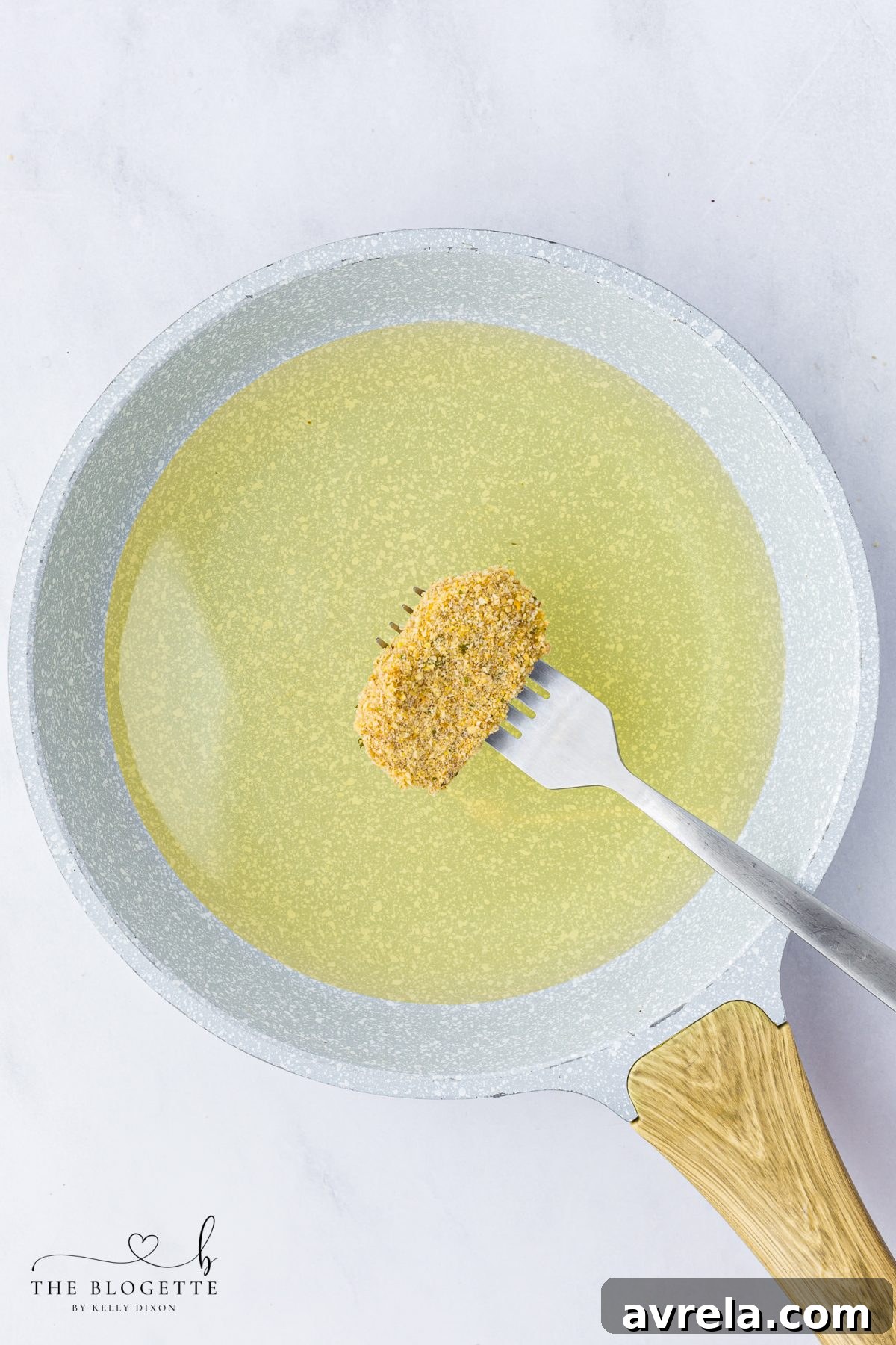 Frozen, breaded mozzarella sticks being carefully placed into hot oil for frying.