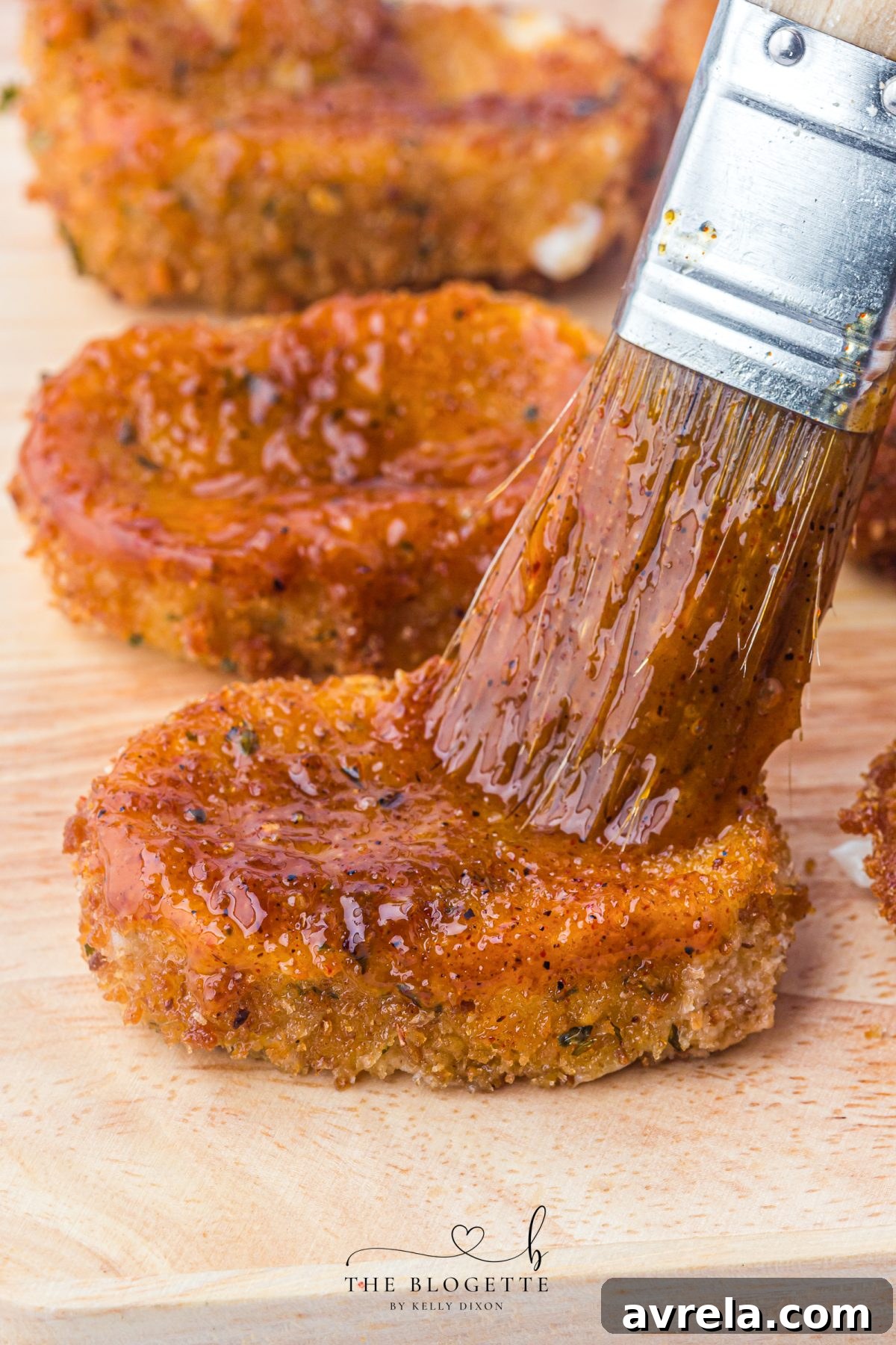 Brushing freshly fried mozzarella sticks with vibrant Nashville hot sauce.