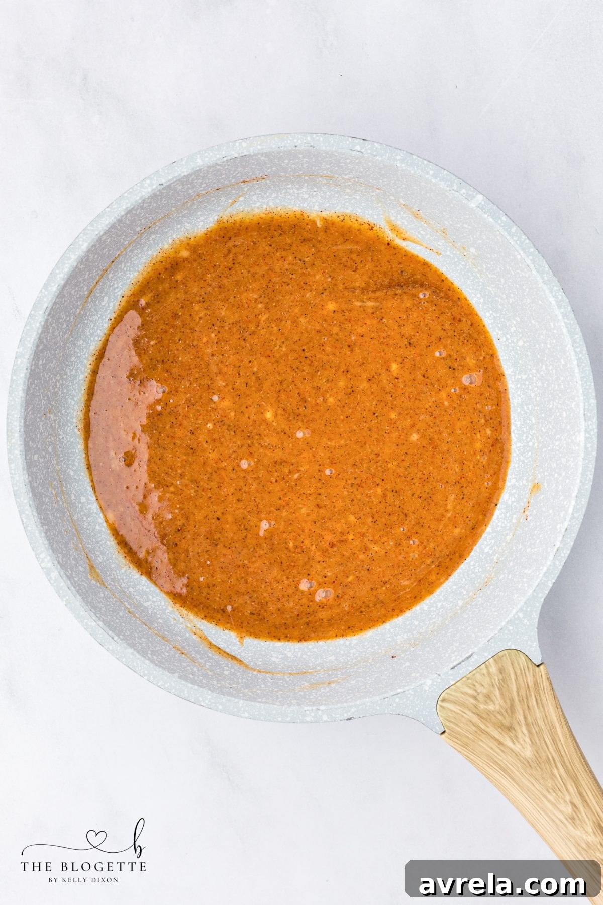 The Nashville Hot Sauce simmering gently in a pot, showing its rich color and texture.