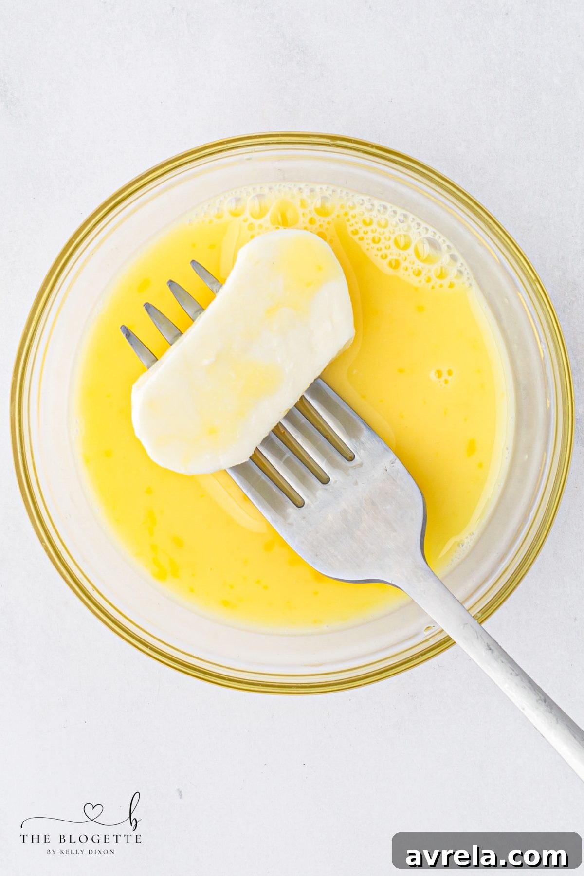 Dipping mozzarella slices into an egg wash mixture for breading.