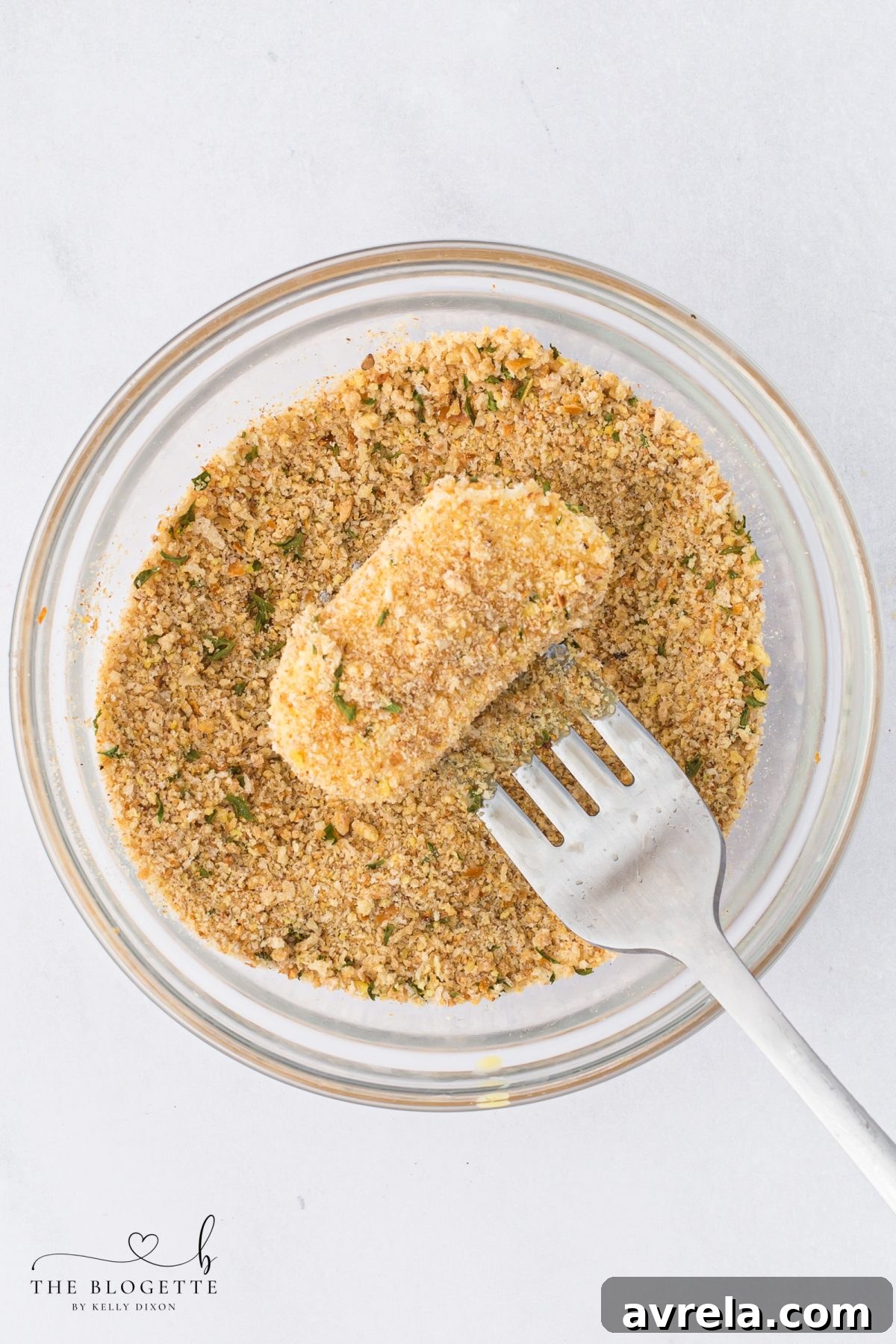Coating mozzarella in breadcrumbs after dipping in egg wash.