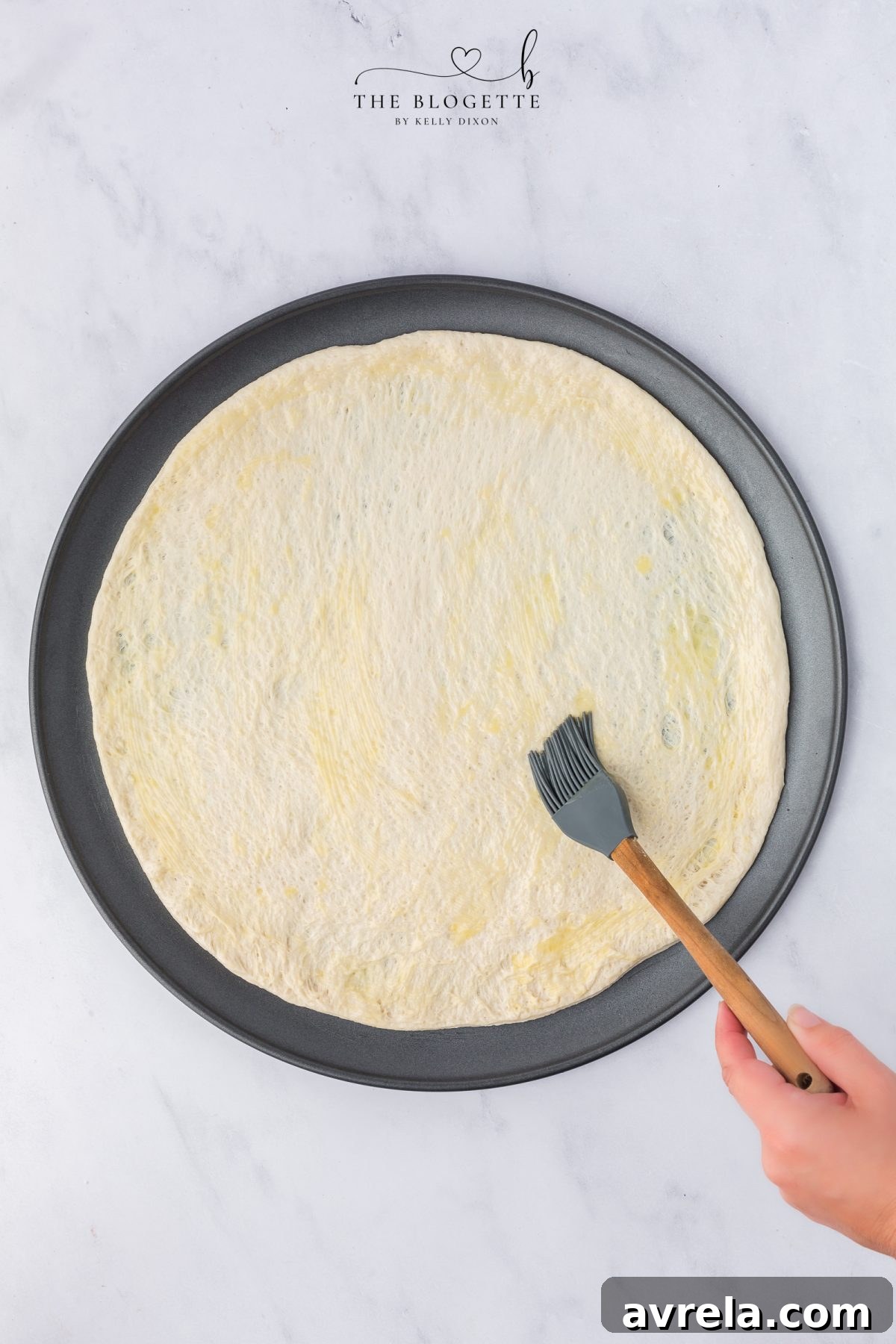 Rise and Shine Pizza 7 Rolling out refrigerated pizza crust onto a baking sheet and brushing it with melted butter.