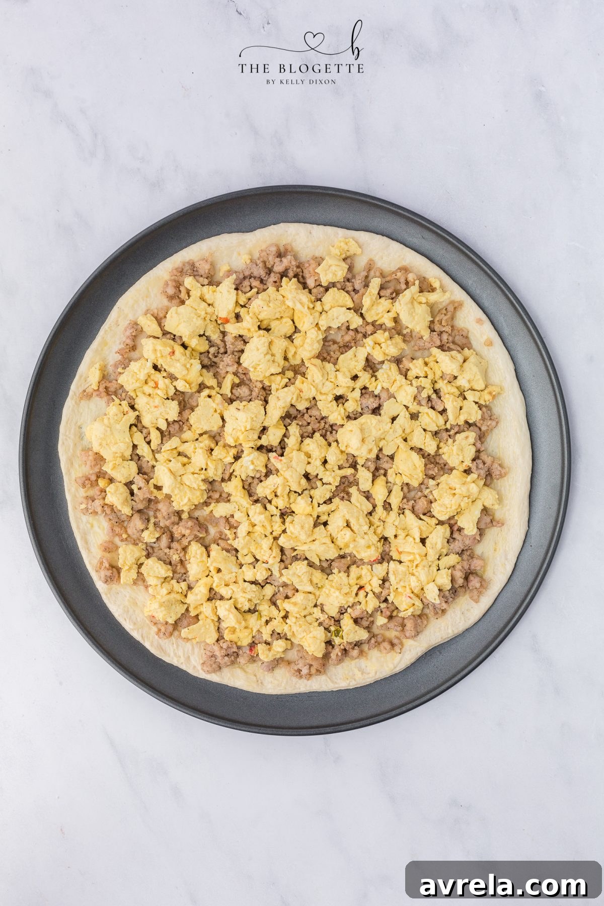 Rise and Shine Pizza 8 Layering cooked sausage and scrambled eggs evenly over the pizza crust.