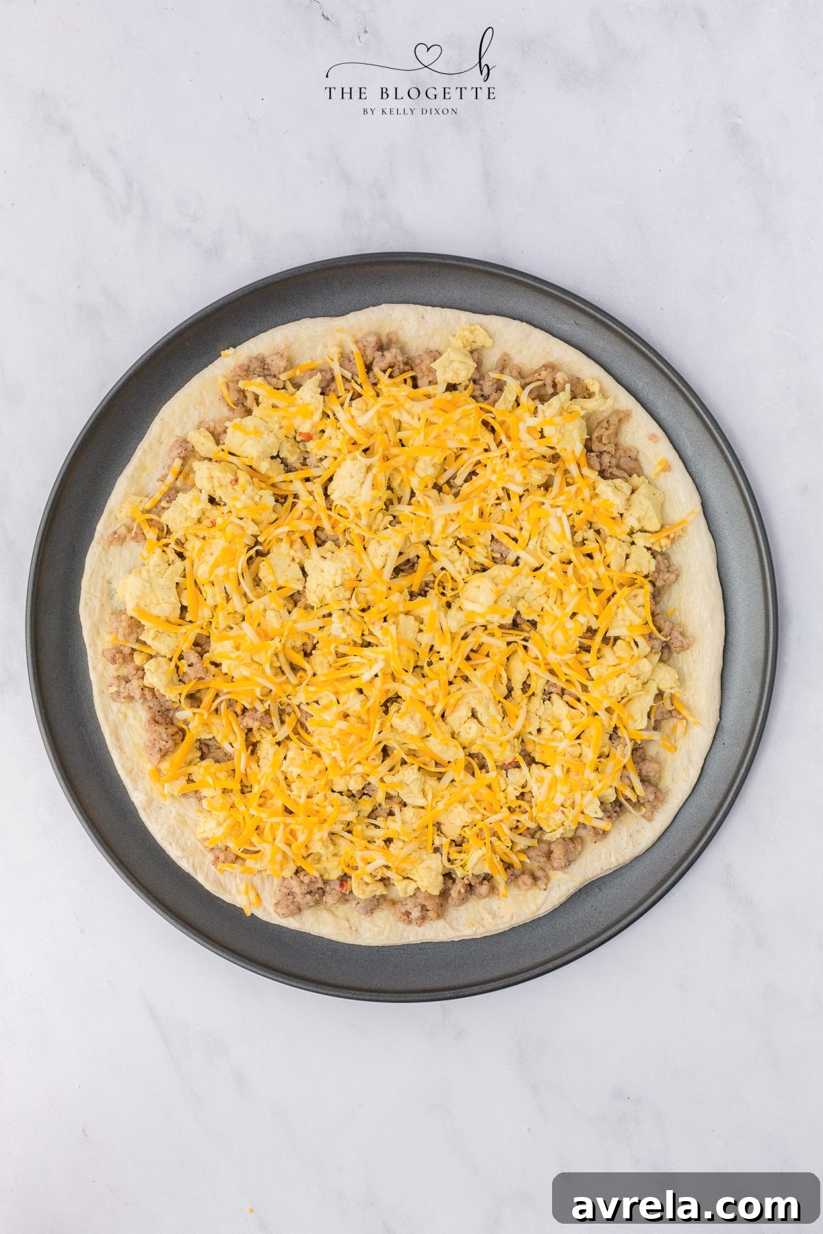 Rise and Shine Pizza 9 Topping the breakfast pizza with Colby Jack cheese before baking.