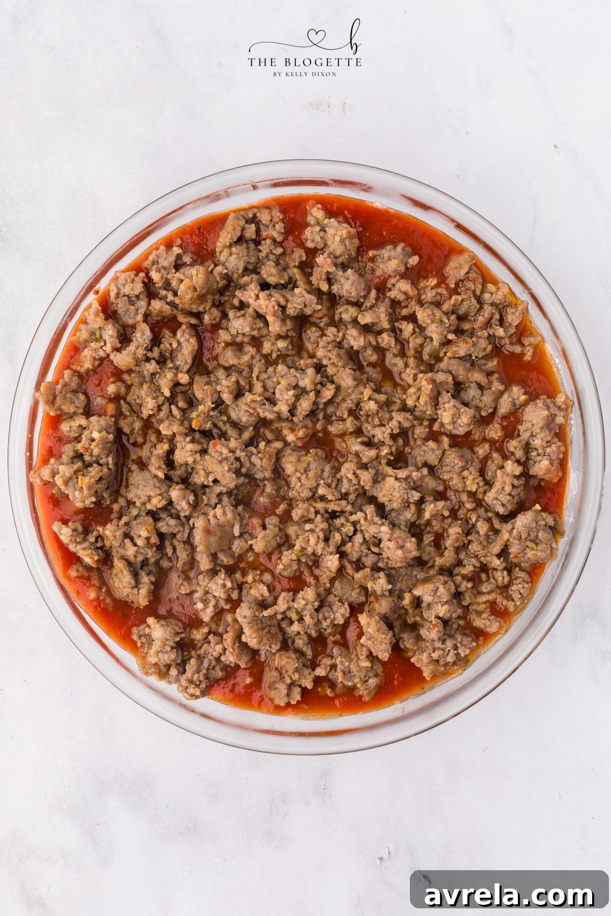 Layering pizza sauce and Italian sausage