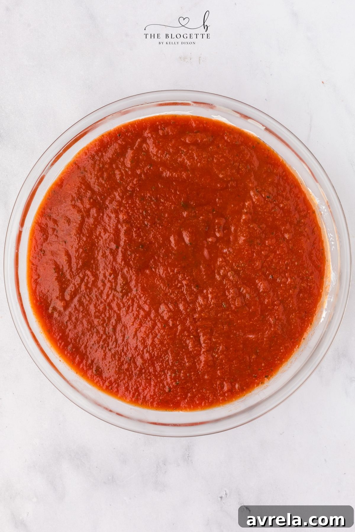 Adding pizza sauce and cooked sausage to the dip