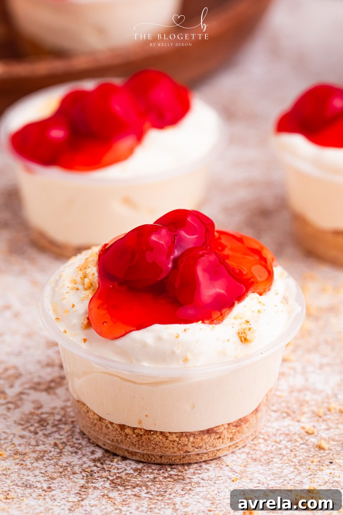 A stunning close-up of Cherry Cheesecake Shots, showcasing the beautiful layers of cheesecake mousse, graham cracker, and bright cherry topping. An ideal no-bake dessert for any occasion, featuring RumChata.