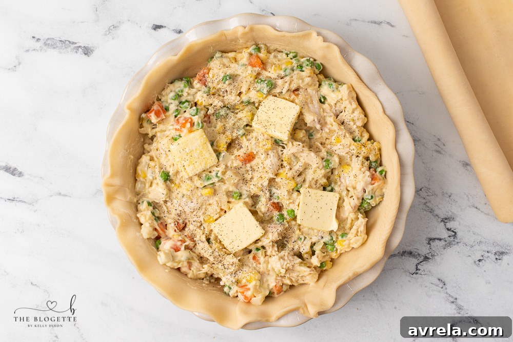 The creamy chicken and vegetable filling being poured into the prepared pie crust.