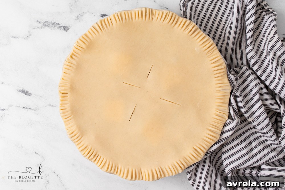 The top crust being placed over the filling, ready for sealing and baking.