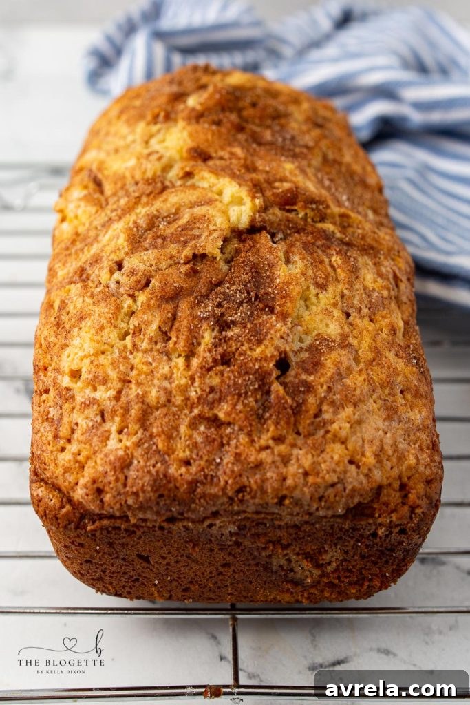 Two loaves of freshly baked Amish Cinnamon Bread on a cooling rack, showcasing the rich, golden-brown crust