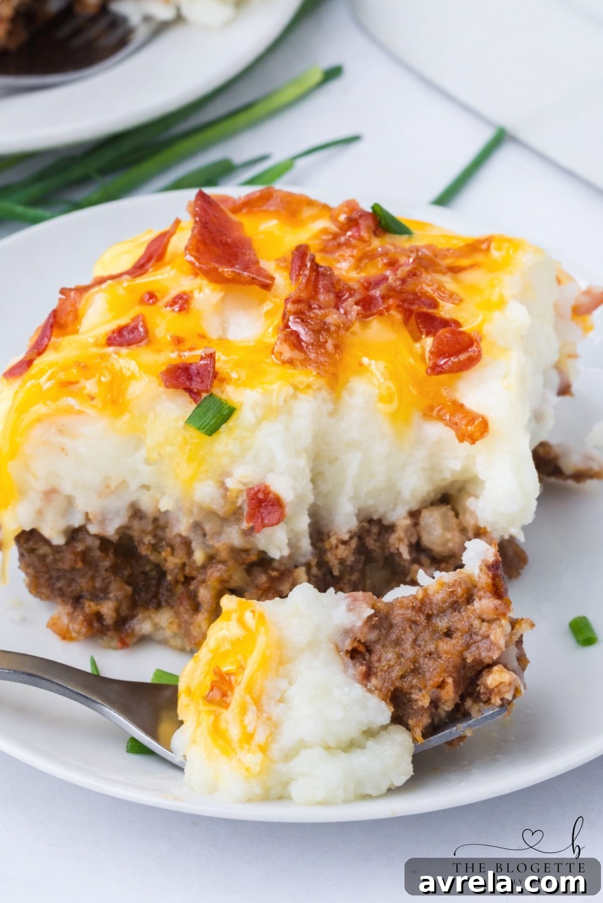 A close-up shot of a sliced Loaded Potato Meatloaf Casserole, highlighting the distinct, flavorful layers of meatloaf, mashed potatoes, and cheesy bacon.