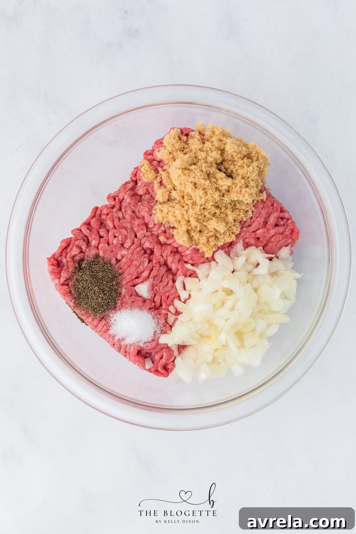 Ground beef and onions being mixed with seasonings in a bowl for the meatloaf base of the casserole.