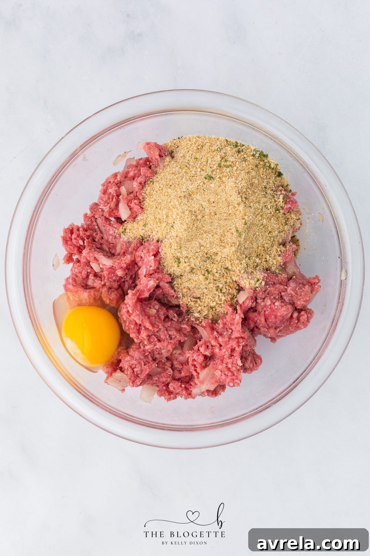 Adding Italian breadcrumbs and an egg to the seasoned ground beef mixture for the meatloaf.