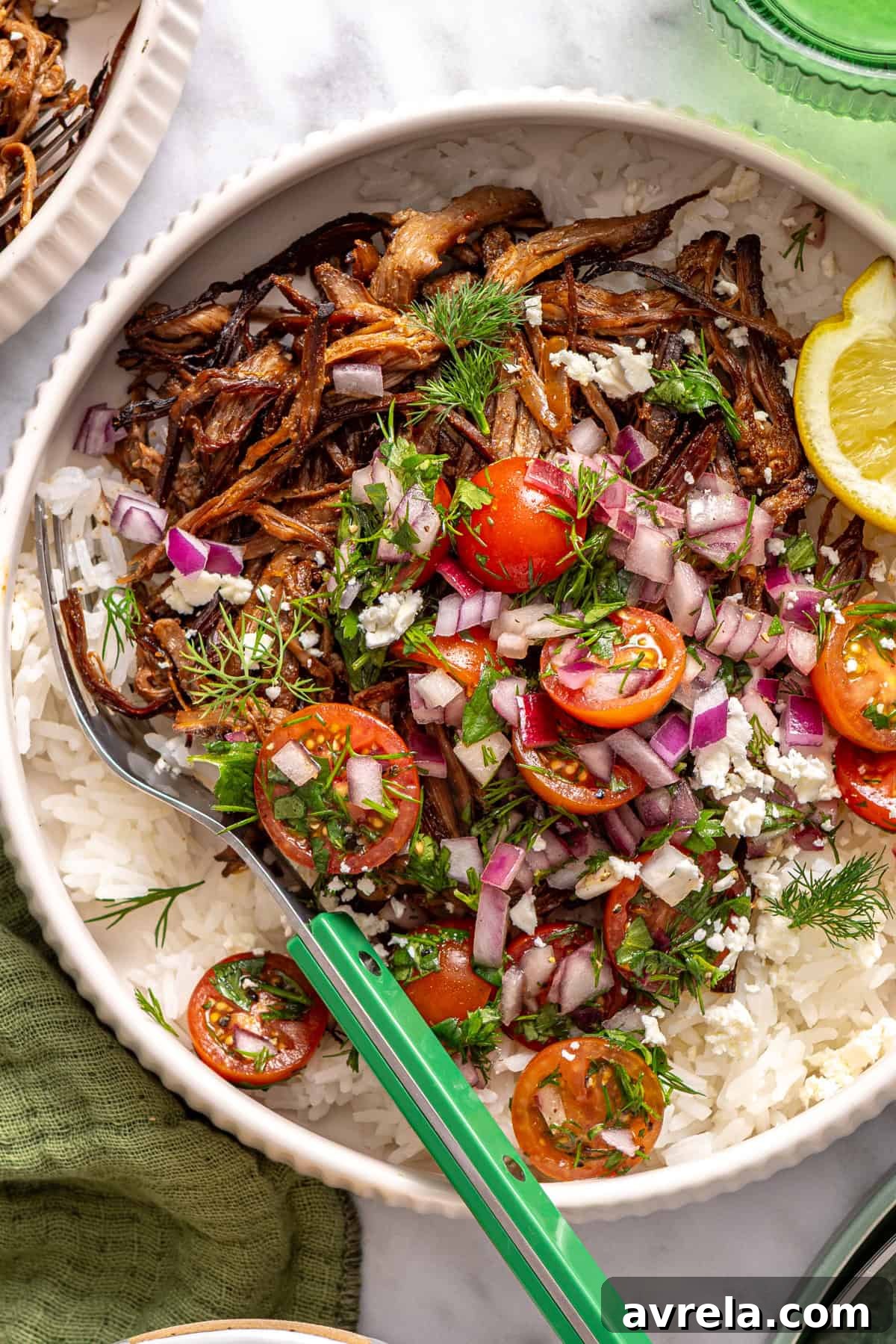 close-up, overhead view of crispy Greek beef bowls with rice, tomato relish, feta, and lemon wedge