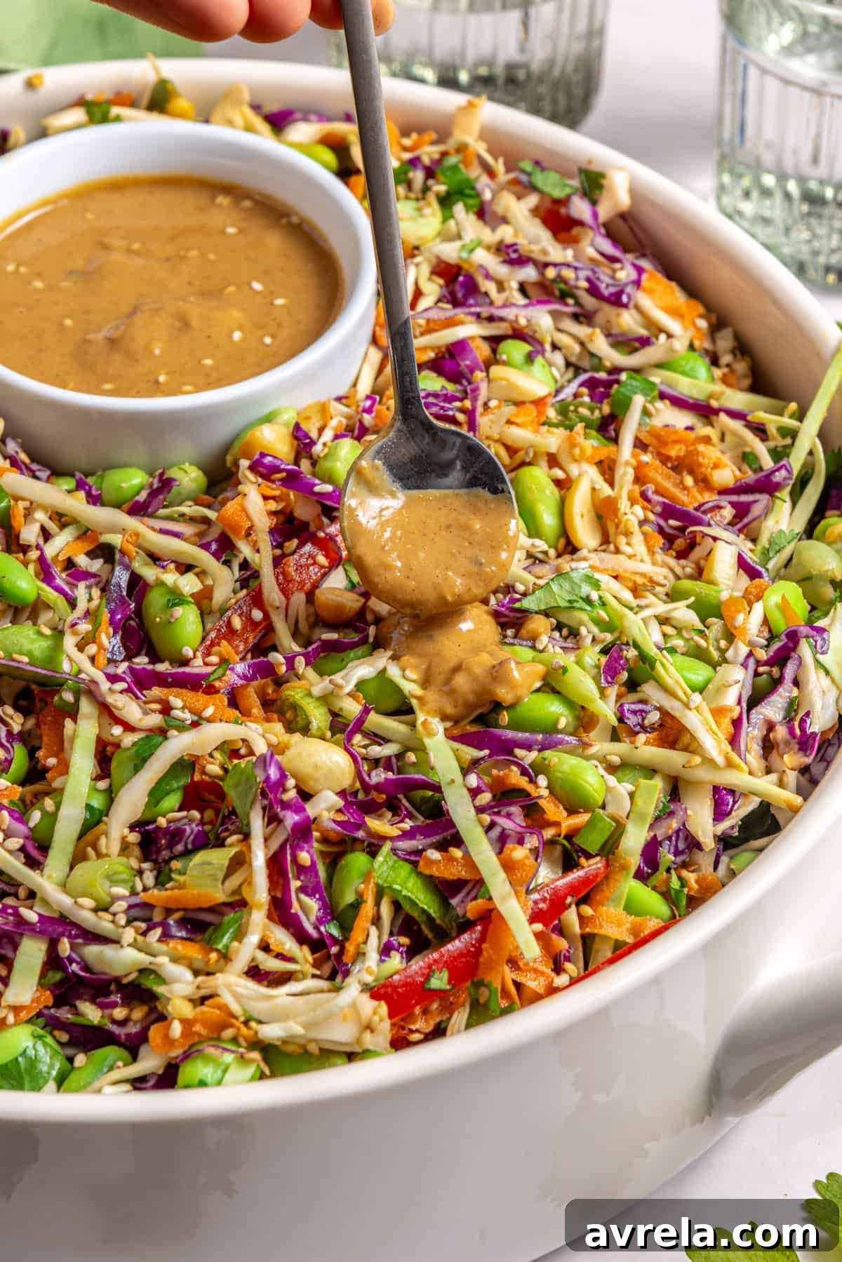 Drizzling sesame peanut dressing over crunchy peanut cabbage salad