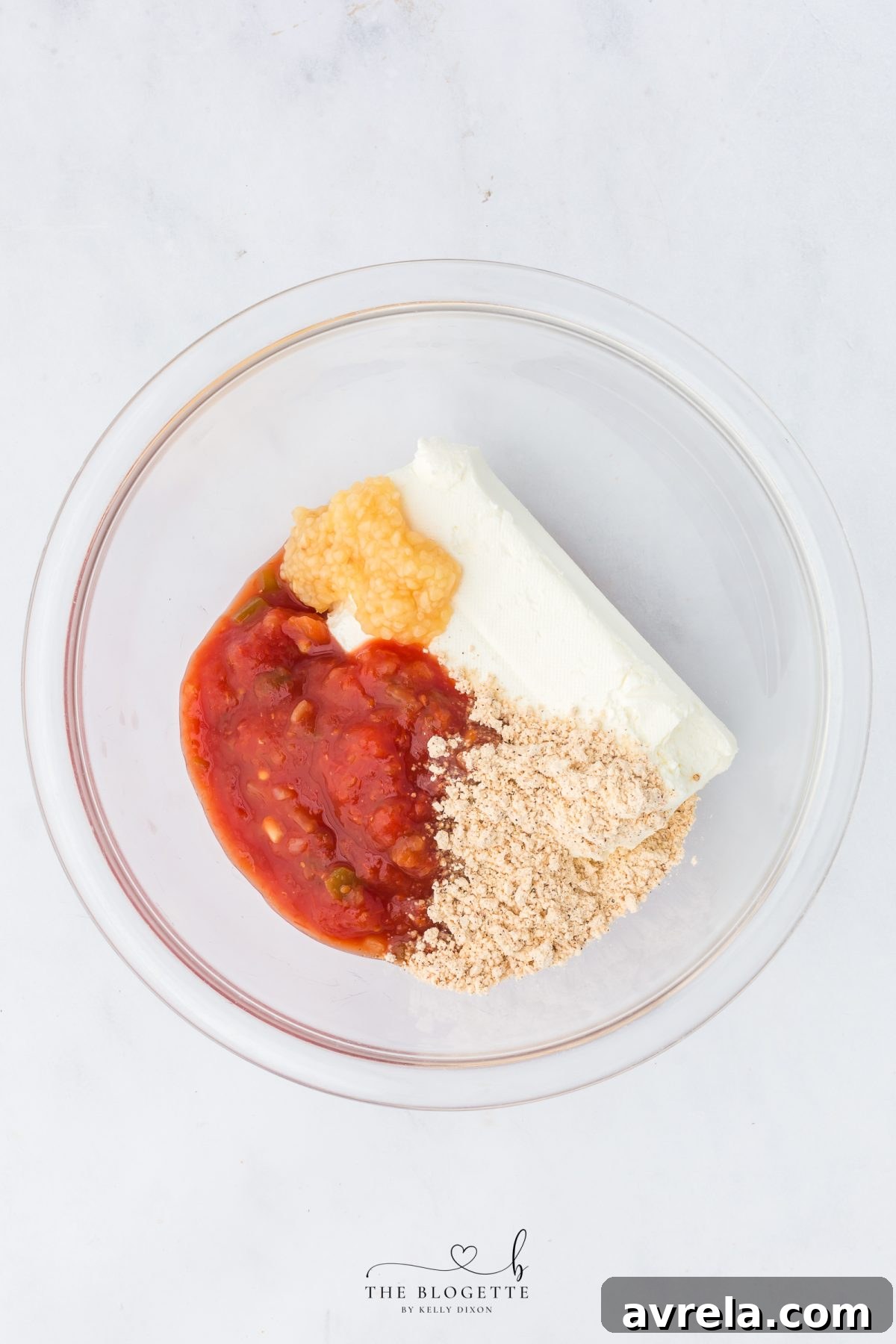 Close-up of cream cheese, salsa, fajita seasoning, and garlic being mixed in a bowl.