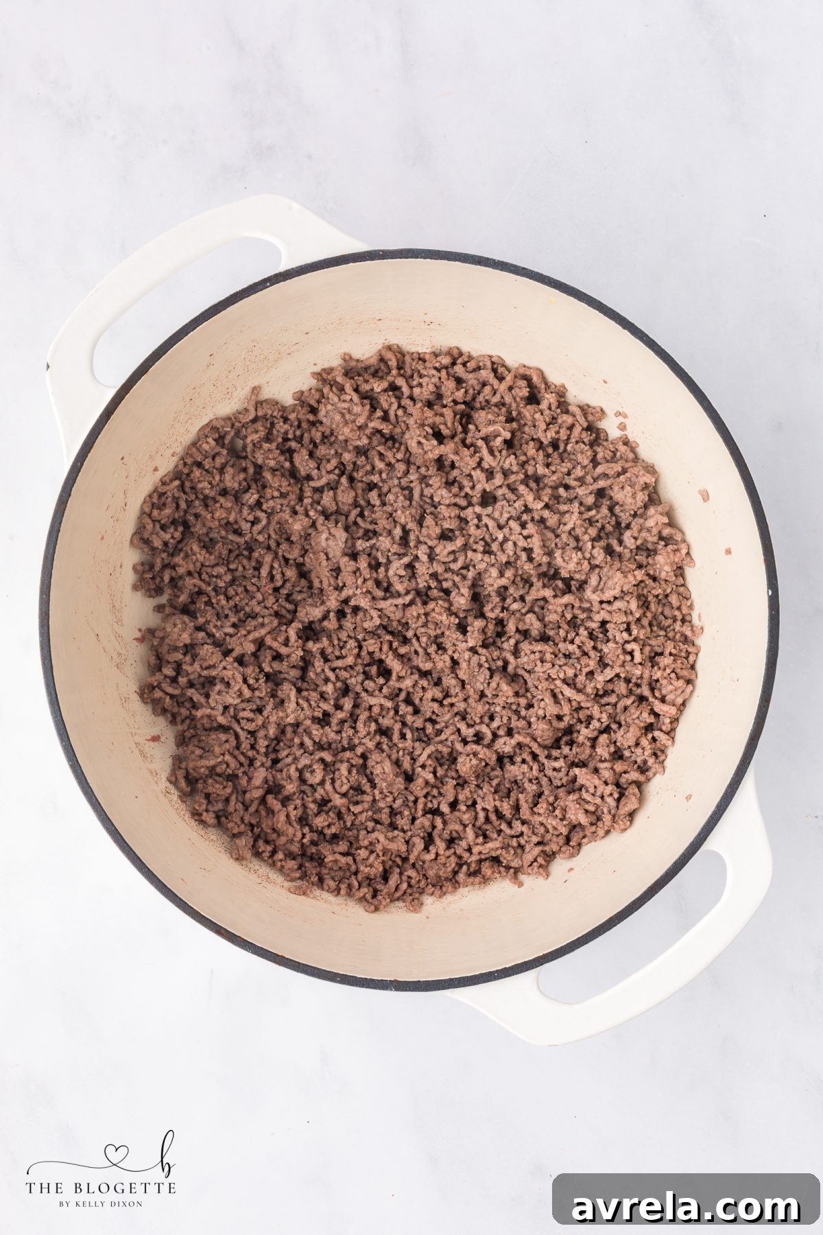 Seasoning the ground beef with salt and pepper as it cooks until fully browned.